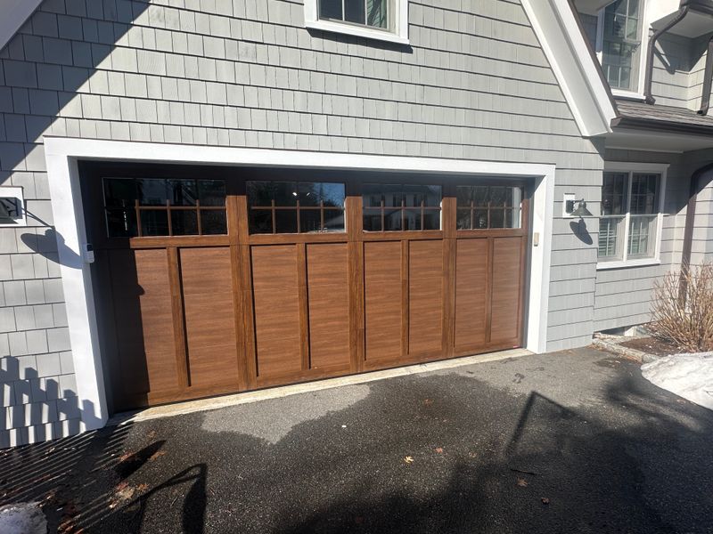 Close-up detail of wood craftsman garage door panels and transom windows in Massachusetts